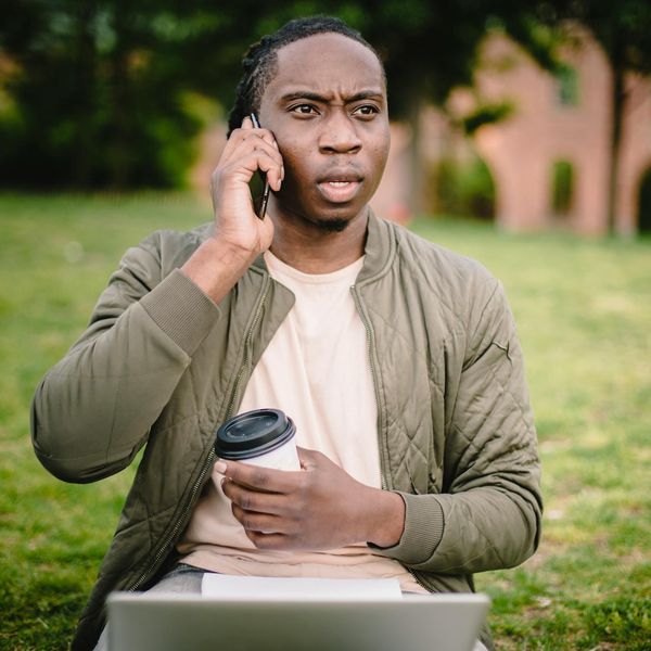 Man stretching gently outdoors in a park with a focused expression.